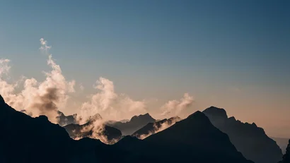 Sonnenaufgang über bewölkten Berggipfeln