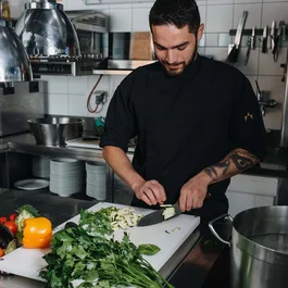 Koch schneidet Gemüse in professioneller Küchenarbeitsbereich