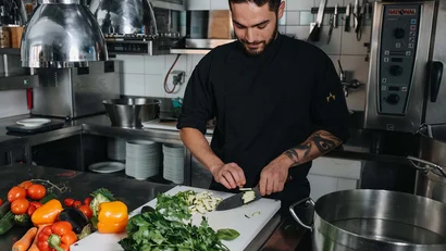 Koch schneidet Gemüse in professioneller Küchenarbeitsbereich