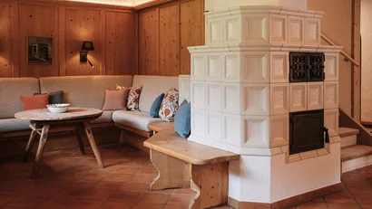 Gemütliche Ecke mit Holzvertäfelung, Ecksofa und traditionellem Kachelofen