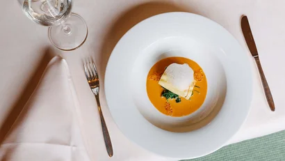 Feines Gericht mit Sauce, Spinat und einer cremigen Garnitur auf weißem Teller