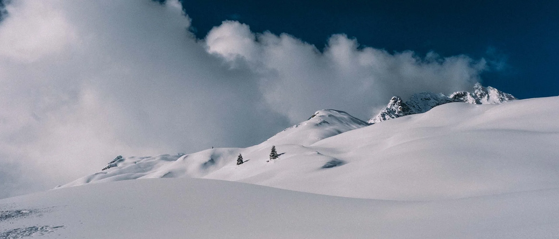 Hotel Aurora am Arlberg: Urlaub für die Sinne Verschneite Berglandschaft mit Bäumen und Wolken am blauen Himmel