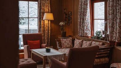 Gemütliches Wohnzimmer mit Holzvertäfelung und Schneeblick durch die Fenster