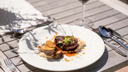 Gegrilltes Steak mit Gemüse und Sauce auf weißem Teller auf Holztisch