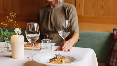 Frau sitzt am Tisch mit eleganter Fischspeise und Wassergläsern