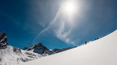 Skifahrer fahren einen sonnigen, schneebedeckten Berghang hinunter