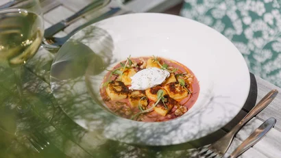 Gegrillte Gnocchi mit Creme und Kräutern auf rosa Sauce in weißem Teller