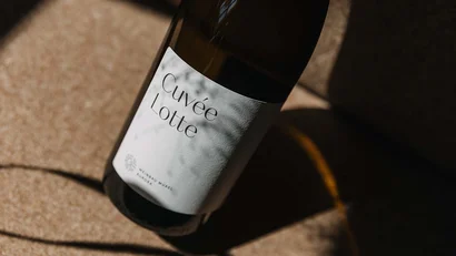 Flasche Cuvée Lotte mit Schatten auf beige Oberfläche