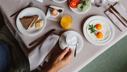 Frühstück mit Spiegelei, Brot, Butter, Ei, Orangensaft und Kaffee