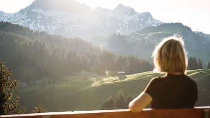 Frau genießt Aussicht auf sonnige Berge und grüne Täler