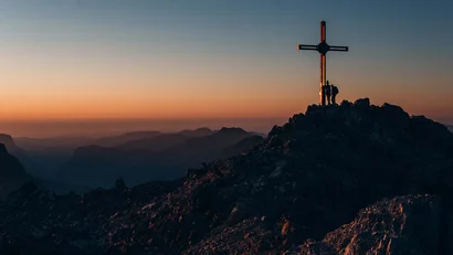Menschen am Gipfelkreuz bei Sonnenuntergang auf einem Berg