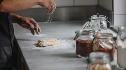 Person bestäubt Teig mit Mehl in der Küche