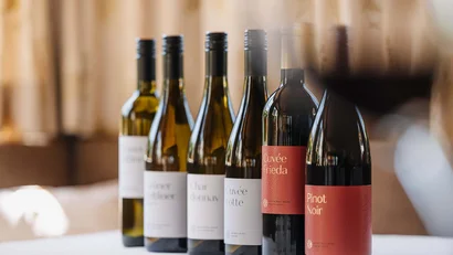 Mehrere Flaschen Wein in einer Reihe mit einem Glas Rotwein im Vordergrund