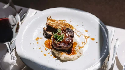 Filetsteak mit Soße auf cremigem Gemüsebrei und Pilzen, begleitet von Rotwein