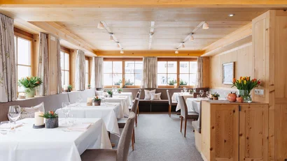 Hell eingerichteter Speisesaal mit Holzwänden und gedeckten Tischen