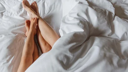 Erwachsene und Kind Beine nebeneinander auf weißem Bettlaken