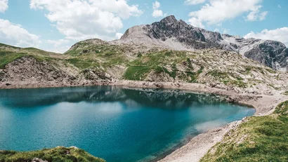 Bergsee mit klarem Wasser und bewölktem Himmel